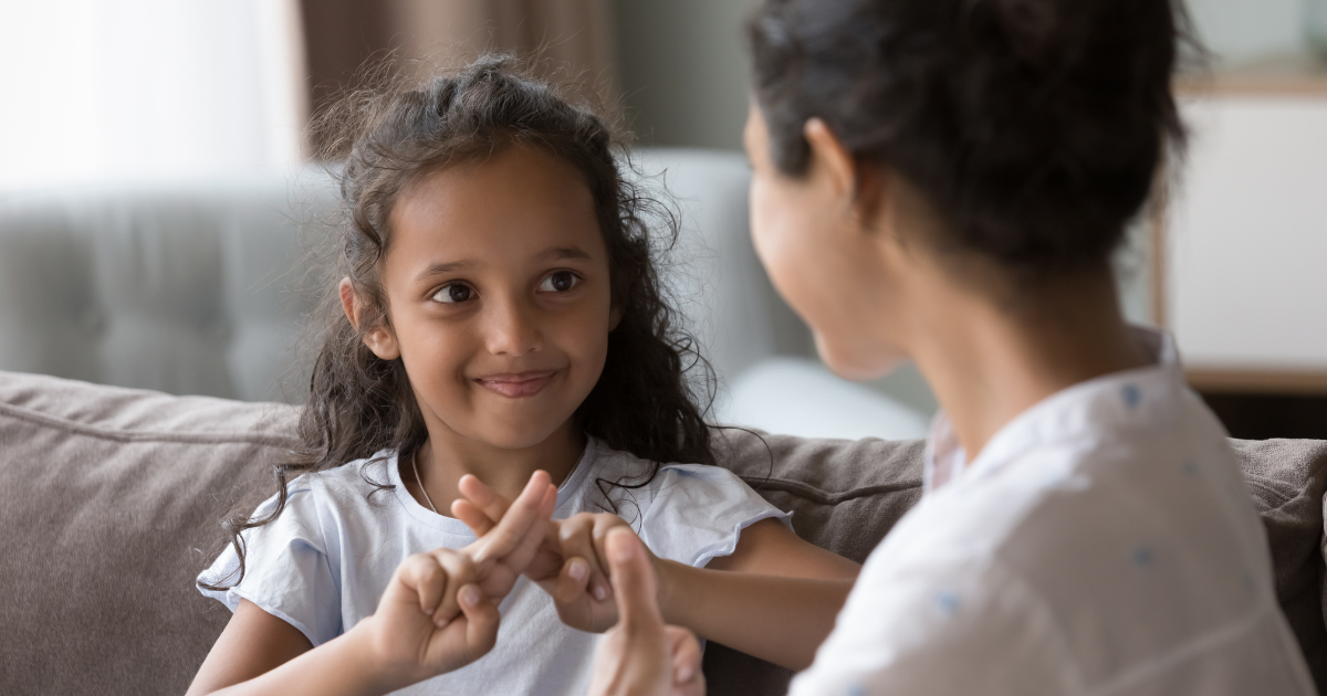 A young girl communicates in sign language with her mother