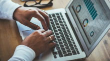 man on computer with mobile phone