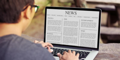 A man reading on the news using laptop