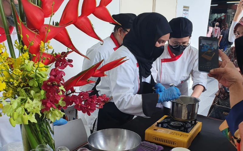 Two Taylors' student chefs preparing food at an outdoor cooking demonstration