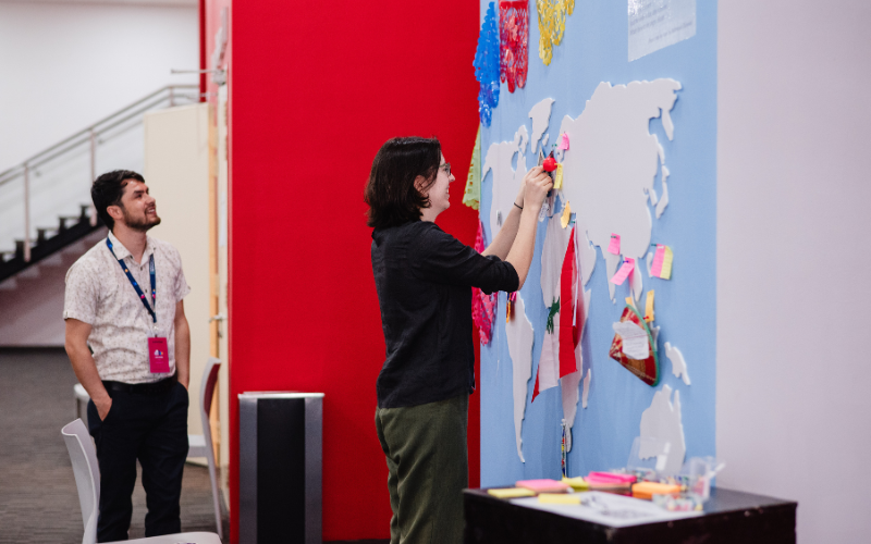 Attendees participating in one of the "Think of Others" activity booths by penning and pinning poems on the world map.