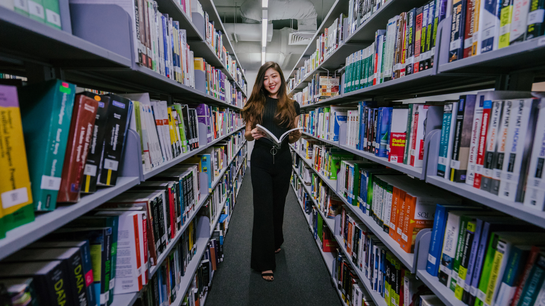woman posing for picture in between library shelves