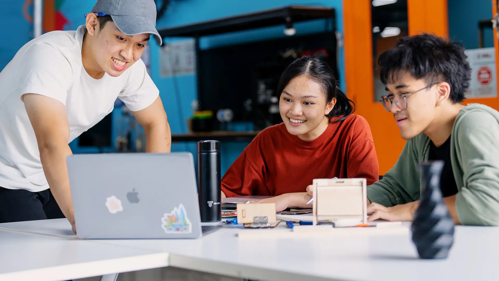 3 students working on project around a laptop