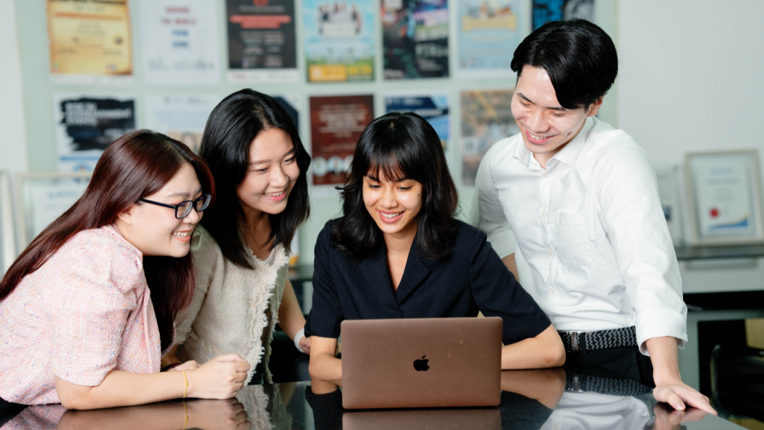 4 students having a discussion around a laptop