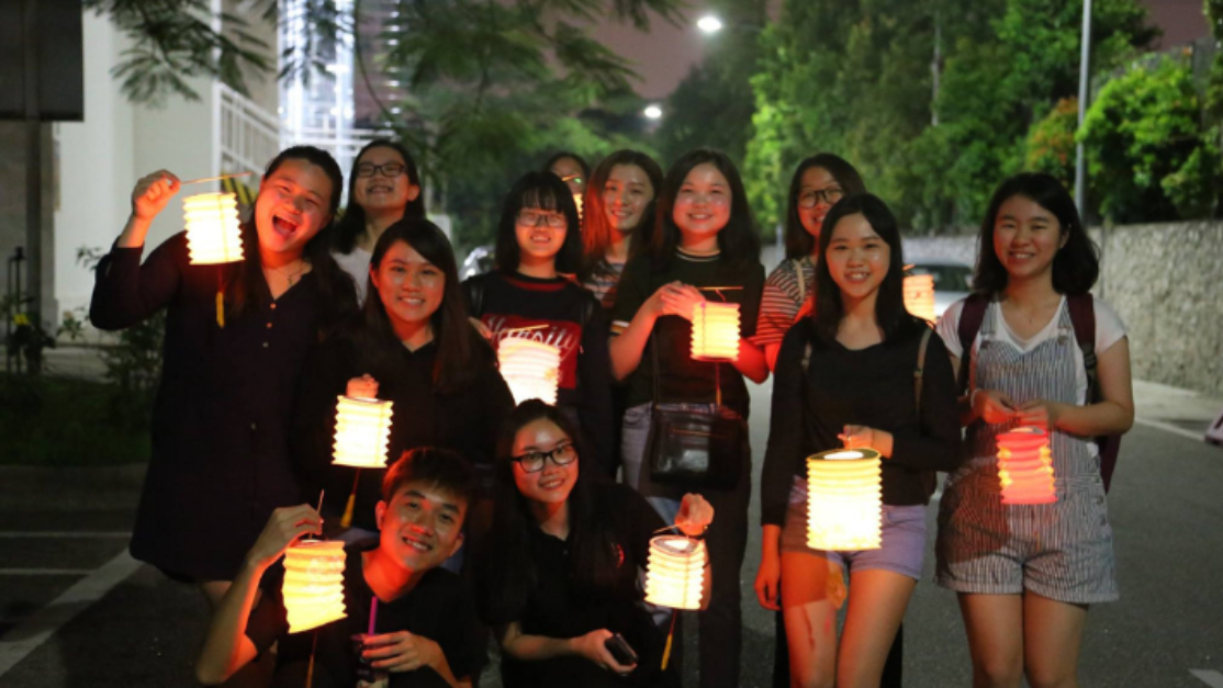 students holding paper lanterns out at night