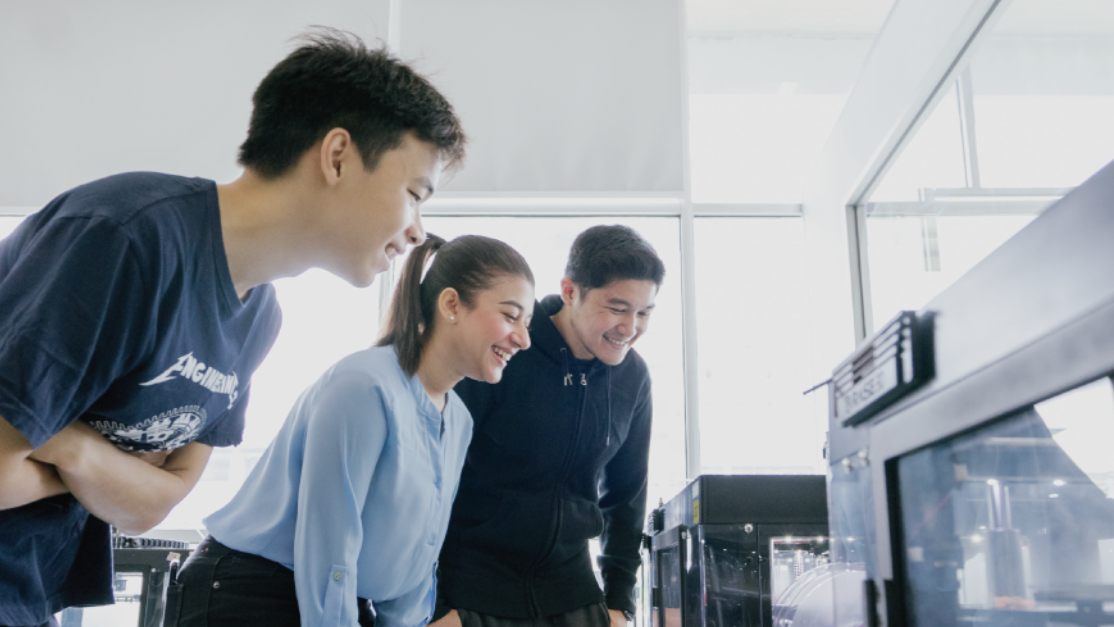 3 students observing engineering machinery