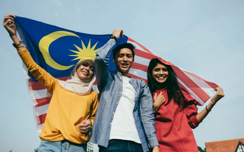 3 malaysians holding up the malaysian flag