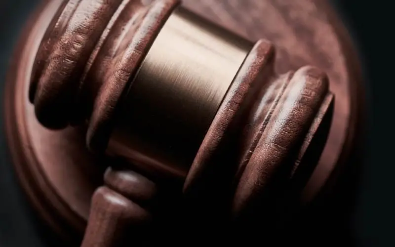 Close-up of a wooden gavel on a table, showcasing the intricacies of its design and the polished brass band that adorns it.