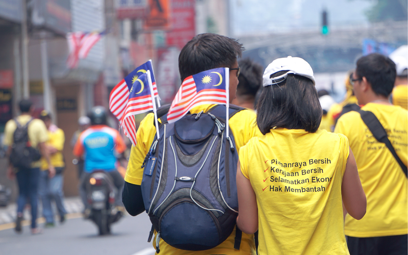 People walking while carrying Malaysian flags