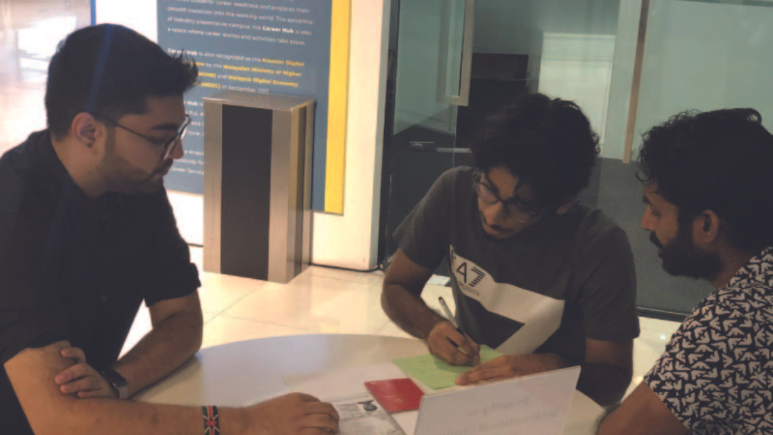 a man tutoring 2 junior students