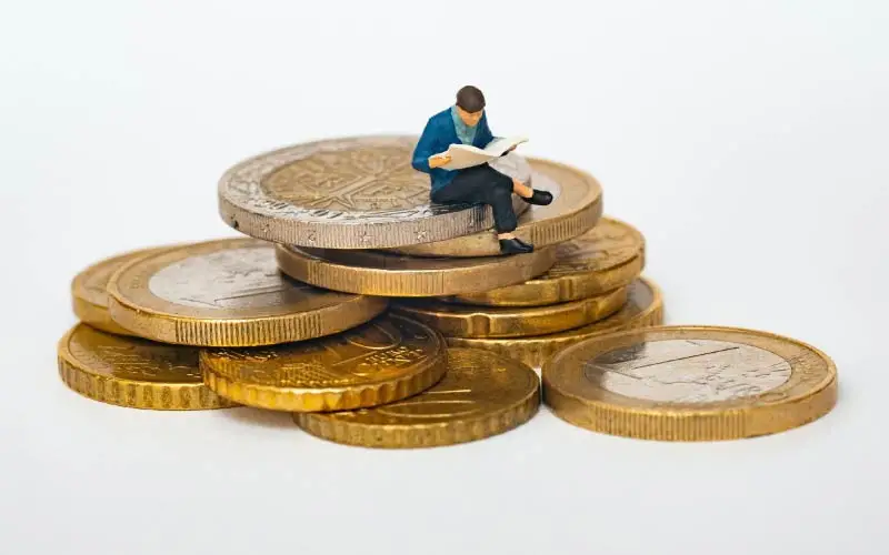 miniature man sitting on coin