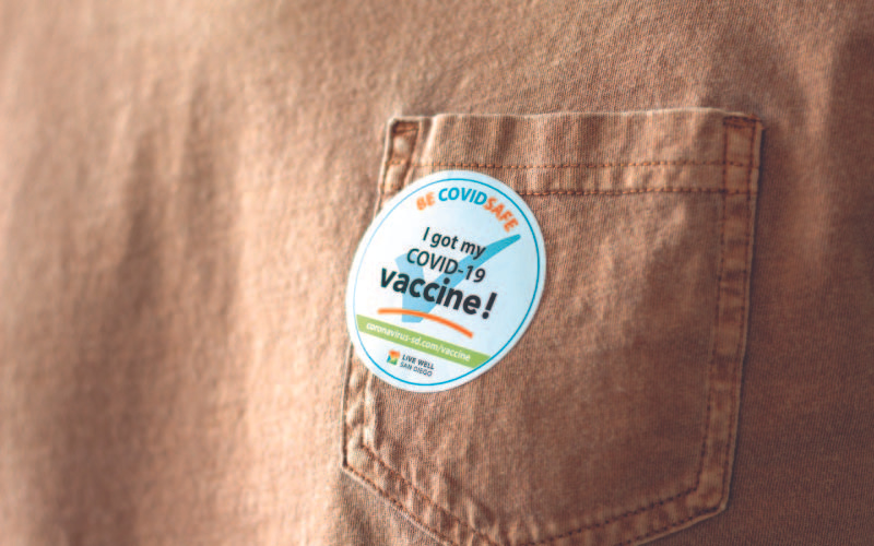 "A sticker stating 'I got my COVID-19 vaccine!' is prominently displayed on a pocket of a khaki garment.