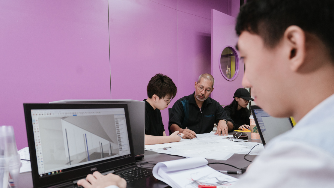 lecturer teaching a student personally while another student uses a laptop