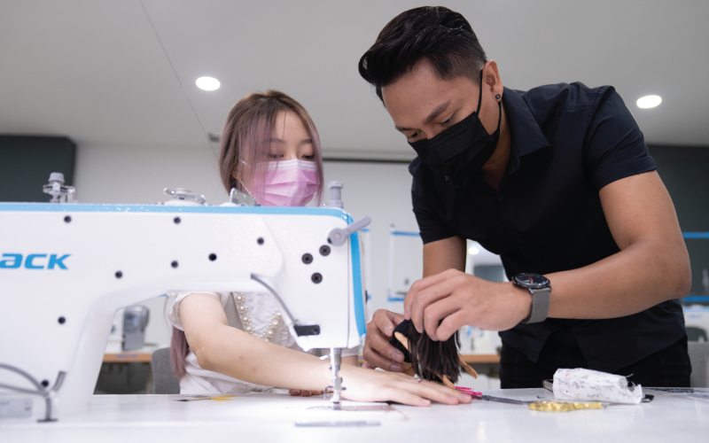 different angle of a lecturer teaching a student how to sew