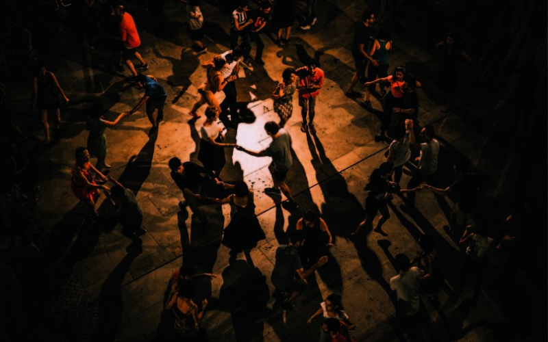 A group of people dancing in a circle under dramatic lighting