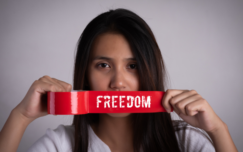 Woman holding read tape that reads "freedom"