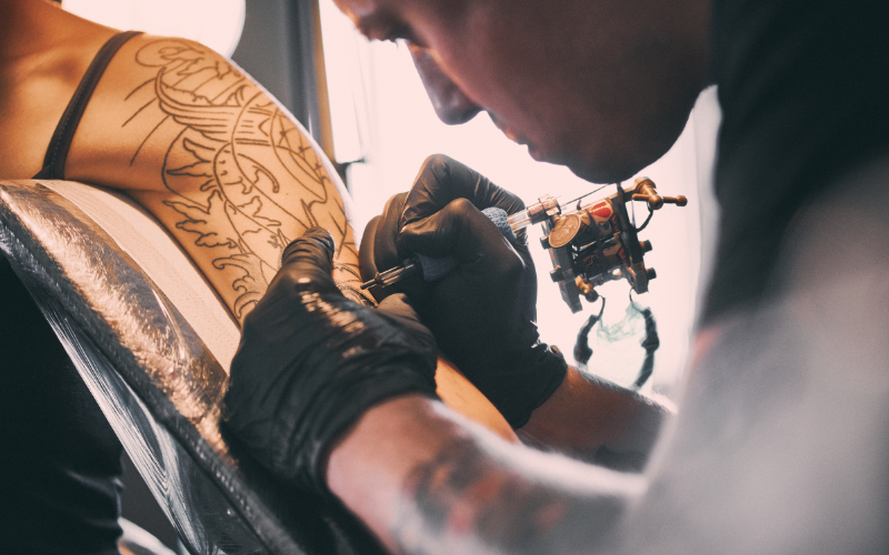 Man tattooing a woman's shoulder