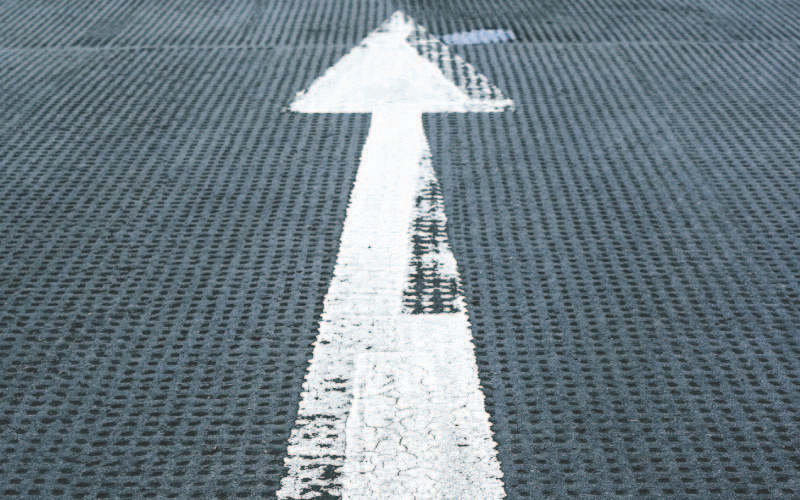 A white arrow on the road showing direction upwards