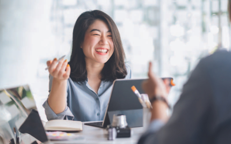 A confident and smiling Asian girl conducting a meeting with her colleague
