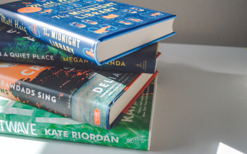 A stack of three books on a white surface with the titles visible on the spine. The top book is 'The Midnight Library' by Matt Haig, followed by 'Where the Crawdads Sing' by Delia Owens, and 'The Heatwave' by Kate Riordan at the bottom.