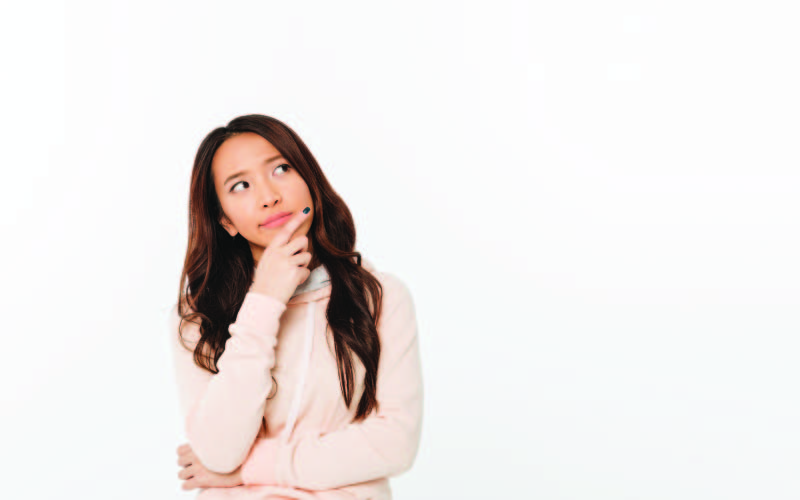 A female college student with long hair wearing a pink hoodie with her hands in a wondering position