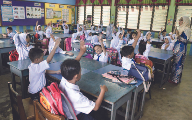 A lively classroom scene with young students wearing white uniforms, raising their hands enthusiastically to answer a question.