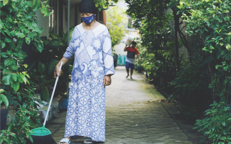 Woman sweeping the floor outside