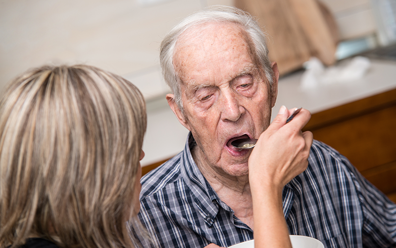 Woman feeding an elderly man