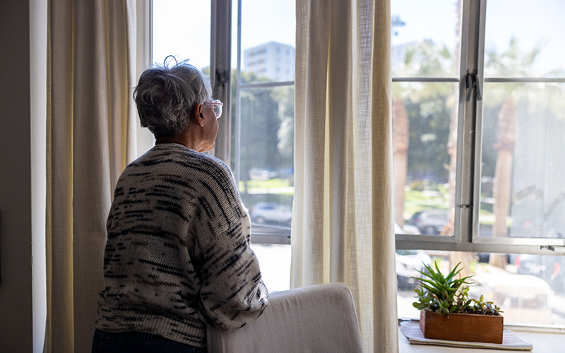 Lonely elderly woman looking out the window