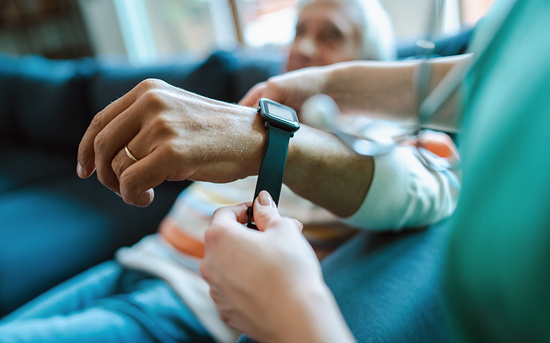 Nurse helping an elderly man wear a smartwatch