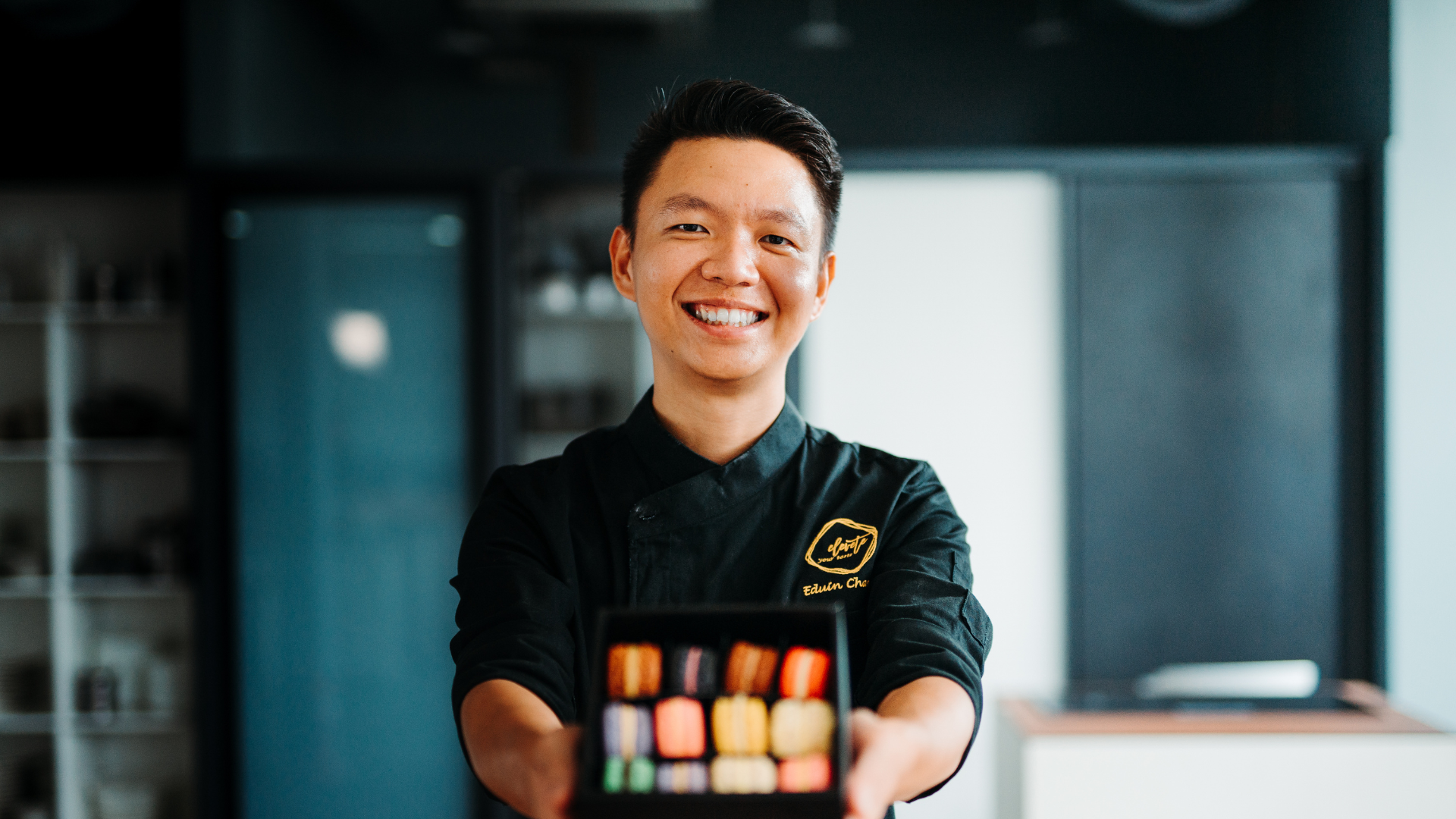 Edwin Chan holding a box of macaroon while smiling at the camera