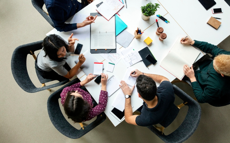 Group of students sitting on a white table discussing on the business project