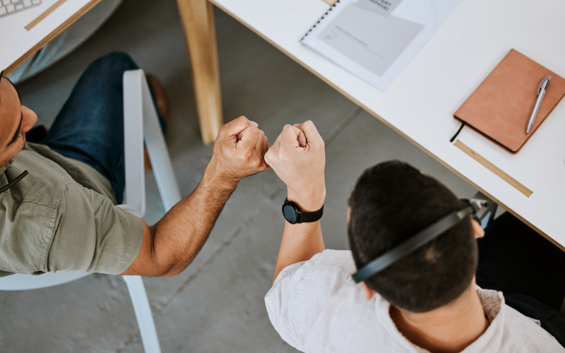 Two students holding fist in the office