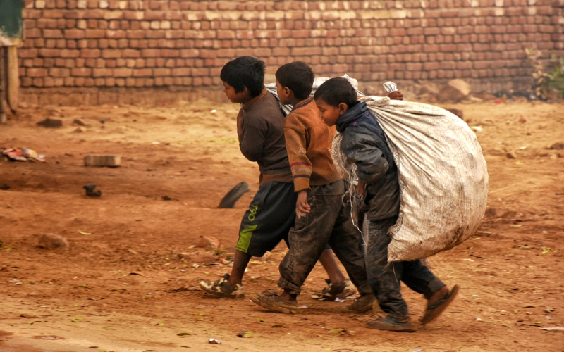 Children living in poverty carrying sacks over their shoulders