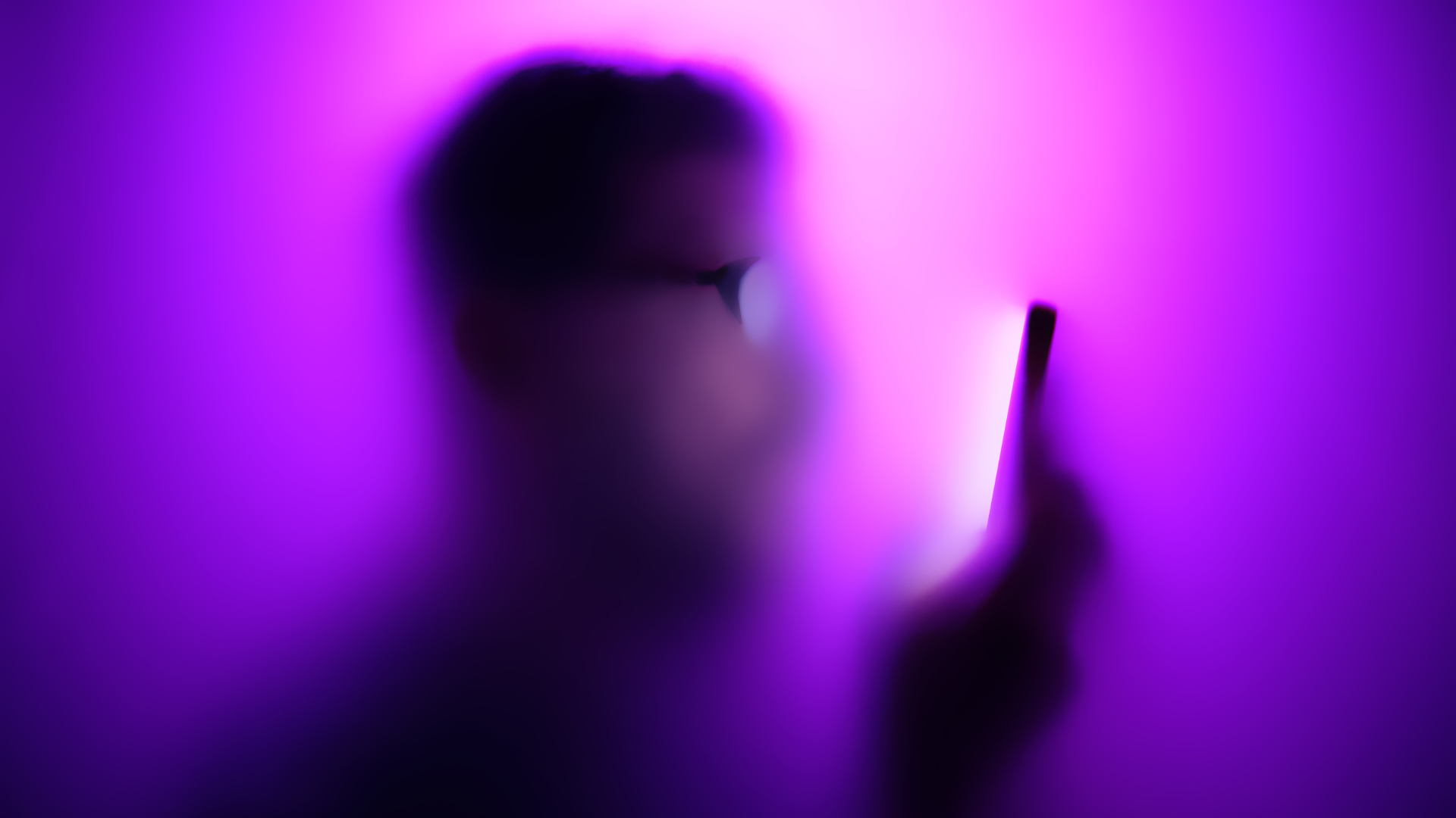 A blurry silhouette of a man on his phone