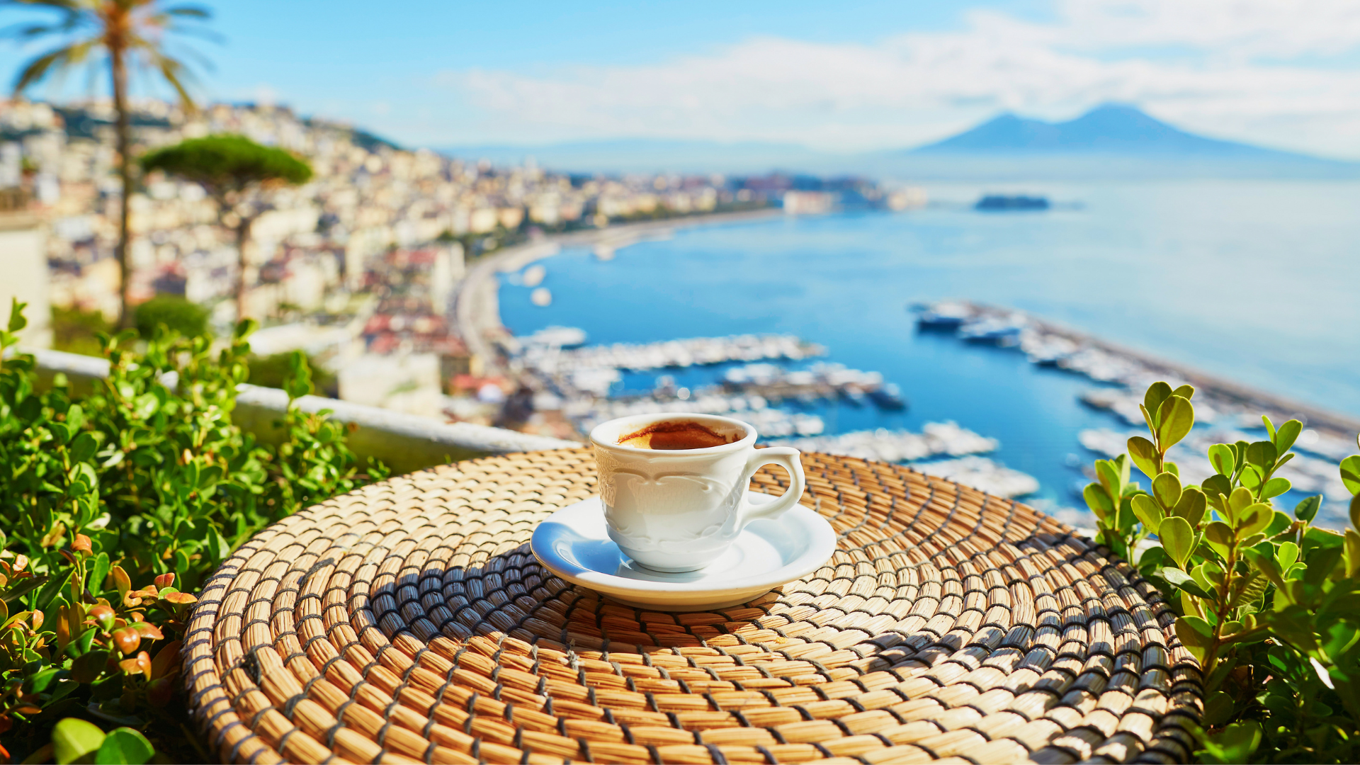 A cup of espresso in the foreground, with the view of Mount Vesuvius in the background