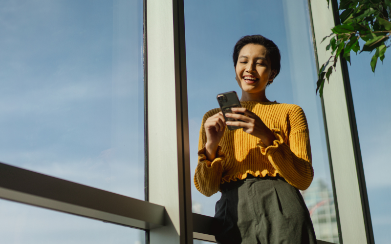 Young woman smiling while looking at the phone