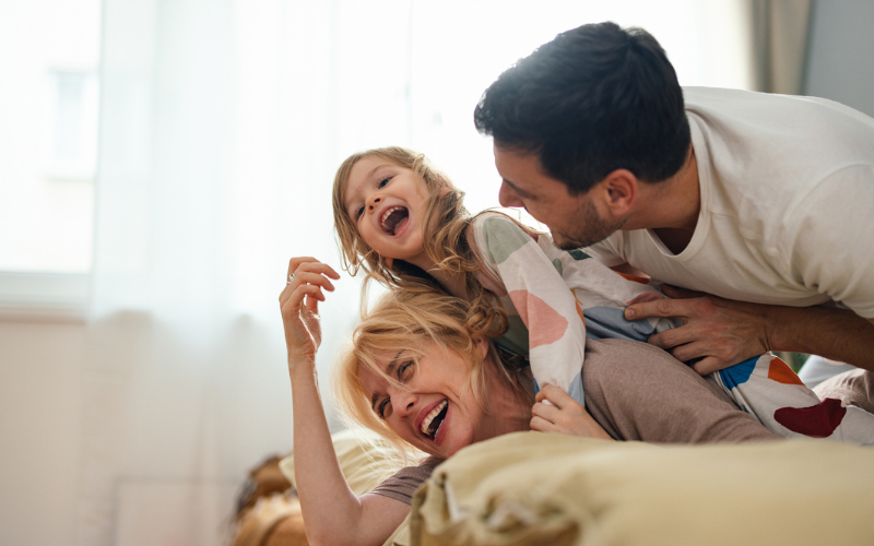 Father, mother and daughter sharing a laugh in bed