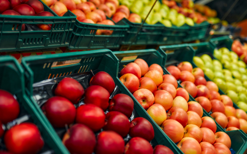 Apples stacked in baskets in a supermarket aisle