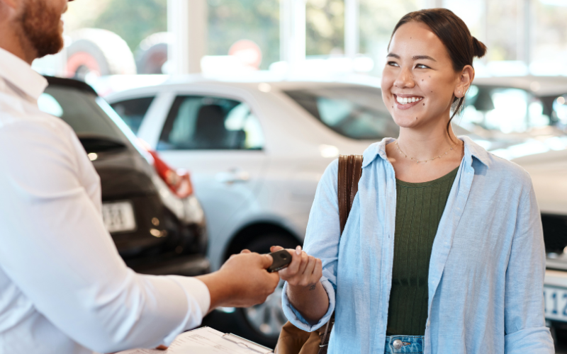  Car salesman handing a car key to a woman