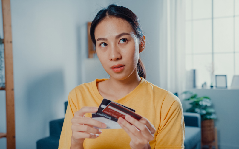 woman figuring out something while holding her stack of credit cards