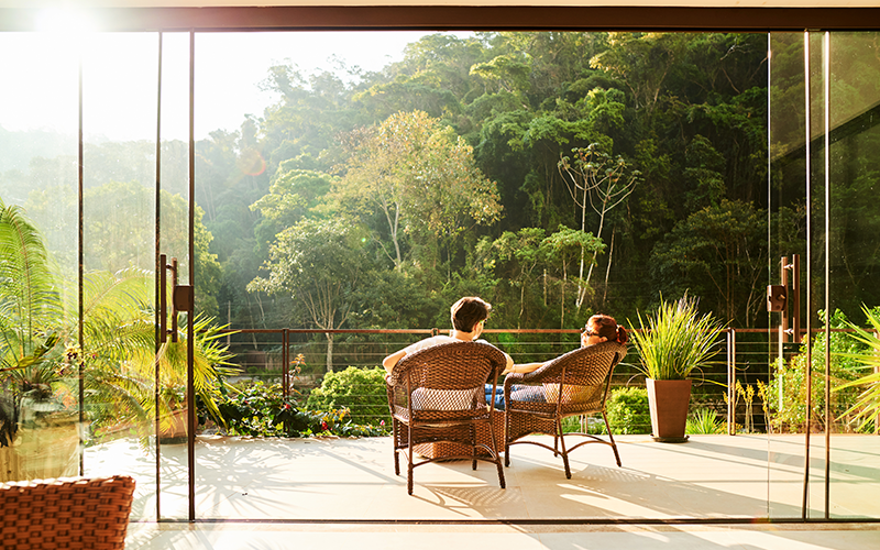 Rear view of a couple relaxing in the chairs at hotel balcony
