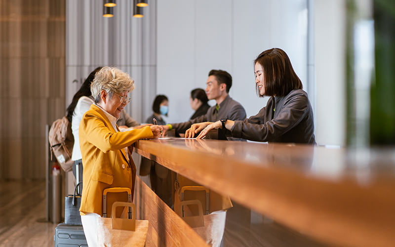 Senior Asian businesswoman checking into a hotel