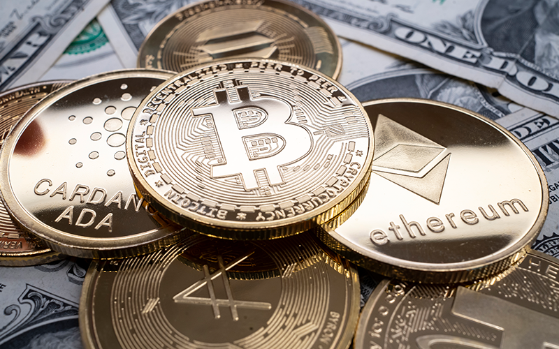 A selection of different cryptocurrency coins piled together over US dollar banknotes