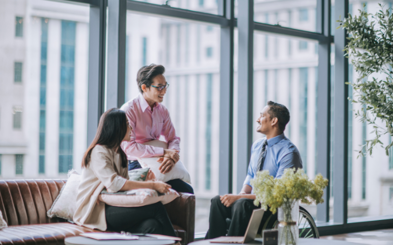 Indian male white collar worker in wheelchair discussion in office lounge with his colleague