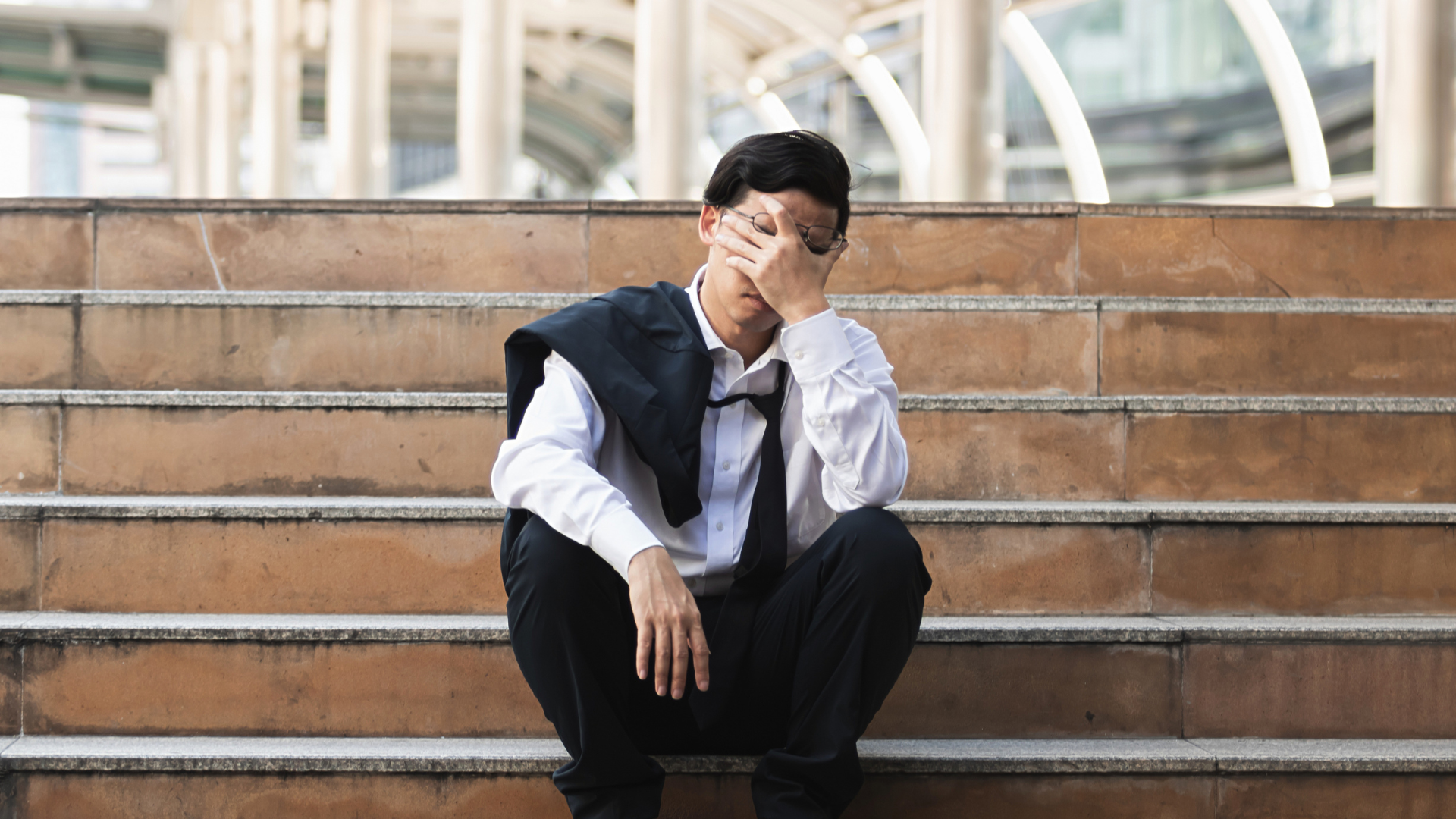 A male intern sitting on the steps, appearing stressed and dejected