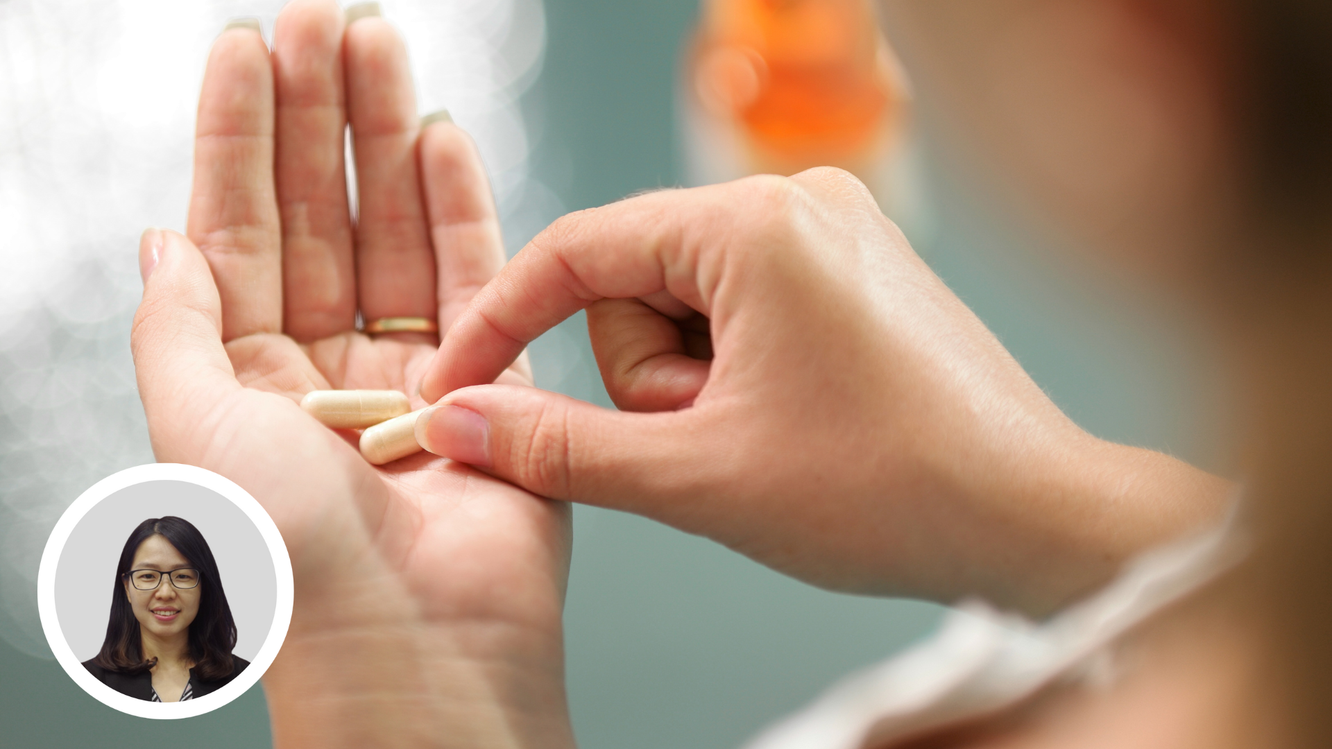 Close up view of young woman holding ginseng vitamins and minerals pills in hand with capsule bottle on table