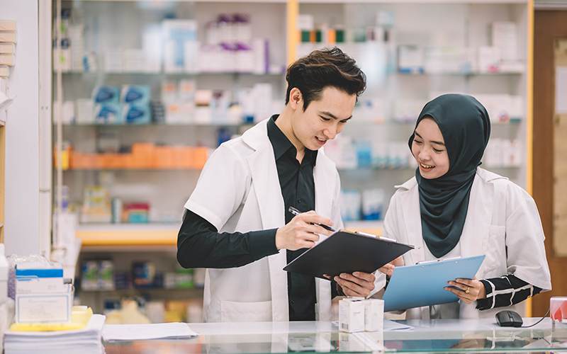 an Asian Chinese pharmacist talking to his Malay female pharmacist colleague
