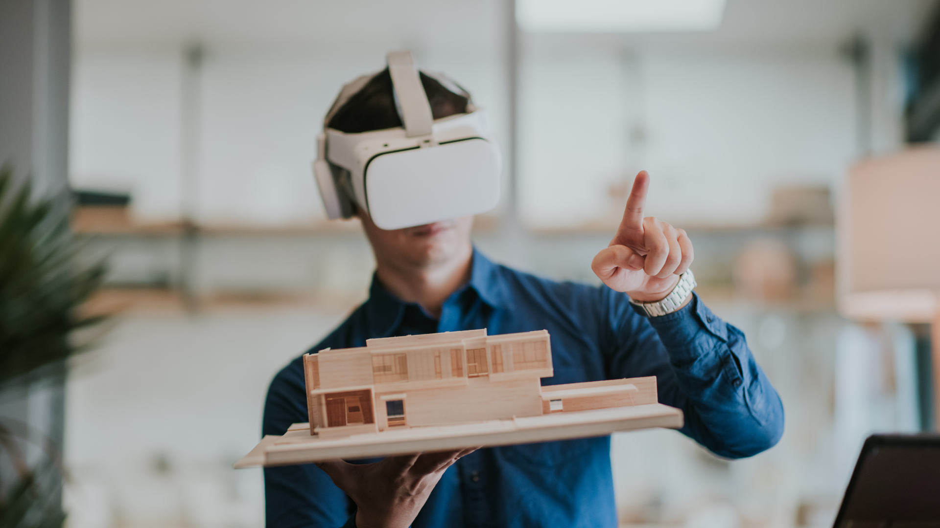 man holding up a model building and wearing vr headset