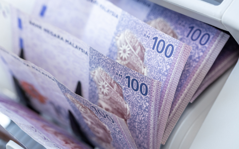 RM100 Malaysian Ringgit banknotes being counted in a machine